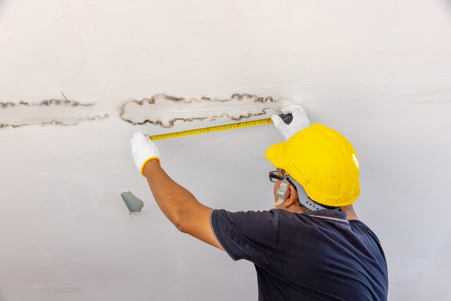 A man is measuring the ceiling, part of a water leak detection service in Atlanta, GA.