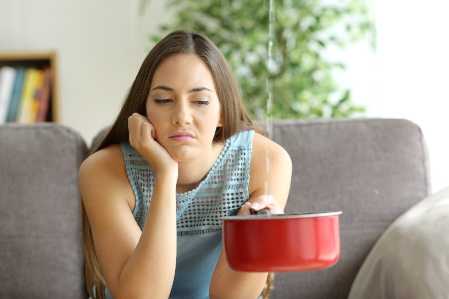 A woman seated on a couch beside a pot indicated an urgent plumbing problem in Atlanta, GA.