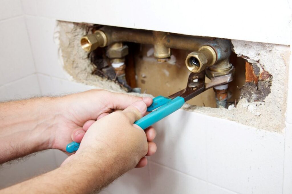 A man uses pliers to repair a bathroom sink during plumbing maintenance in Atlanta, GA.