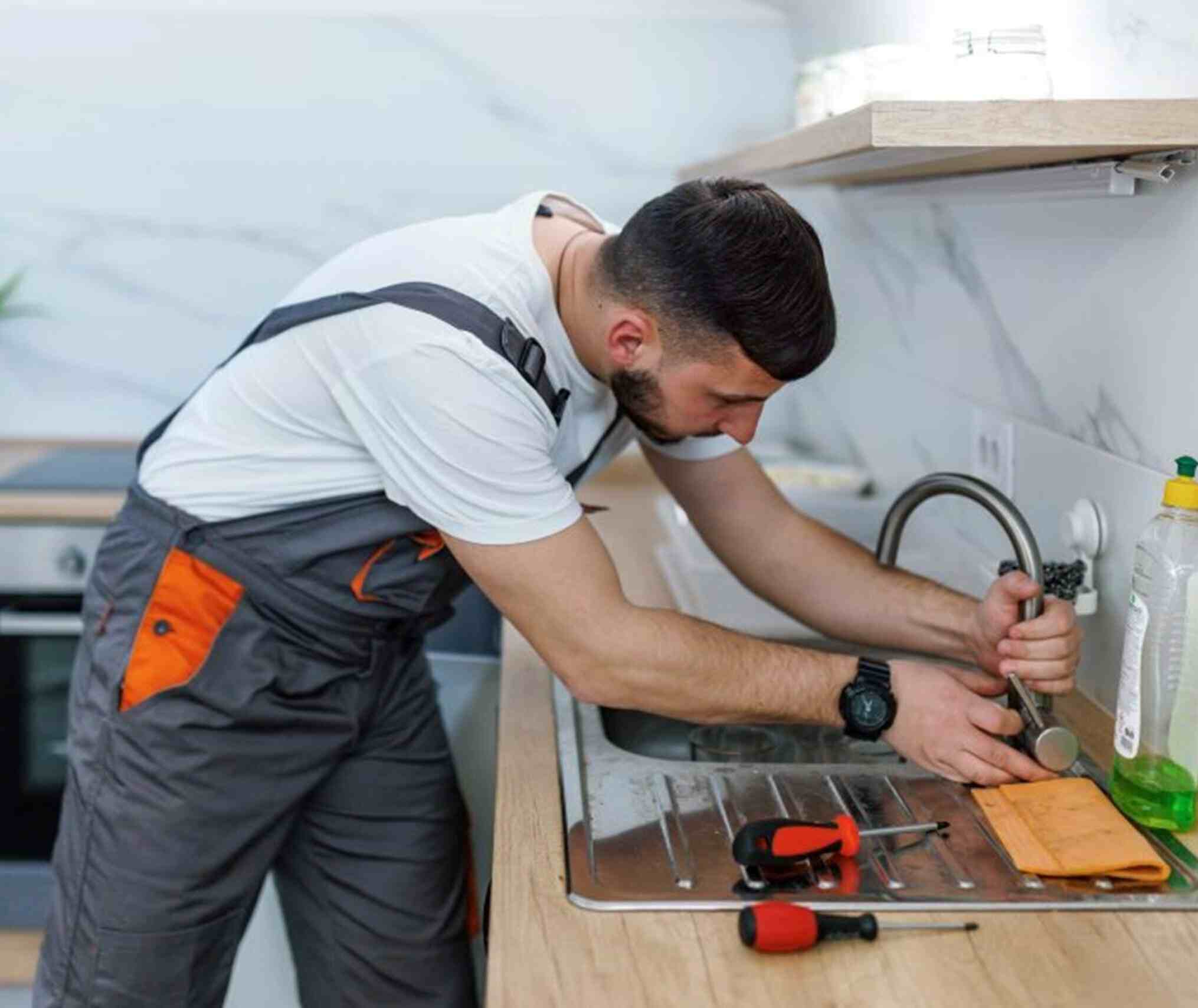 A man repairs a kitchen sink, reflecting his proficiency in plumbing tasks in Atlanta, GA