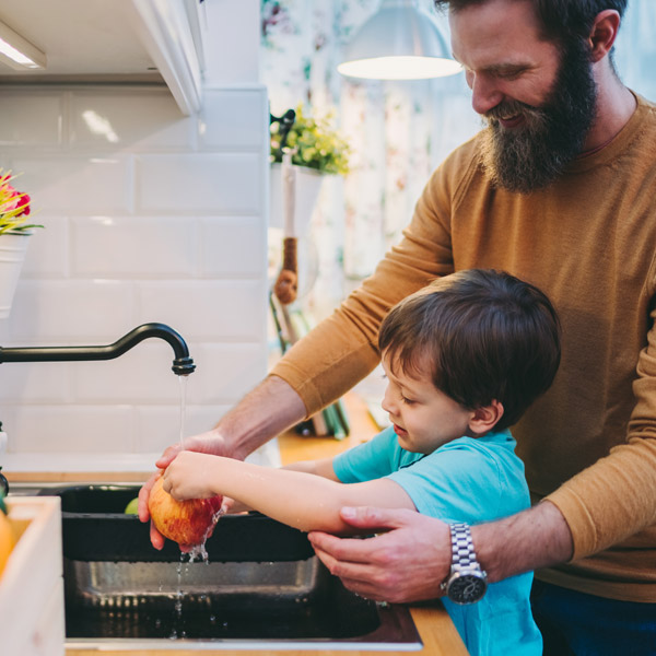 Dad Helping Son to Wash an Apple in the Sink after Water Treatment Service in Buckhead, GA