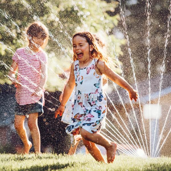 Two cute little children are playing with sprinkler water after repairing it in Tucker, GA.