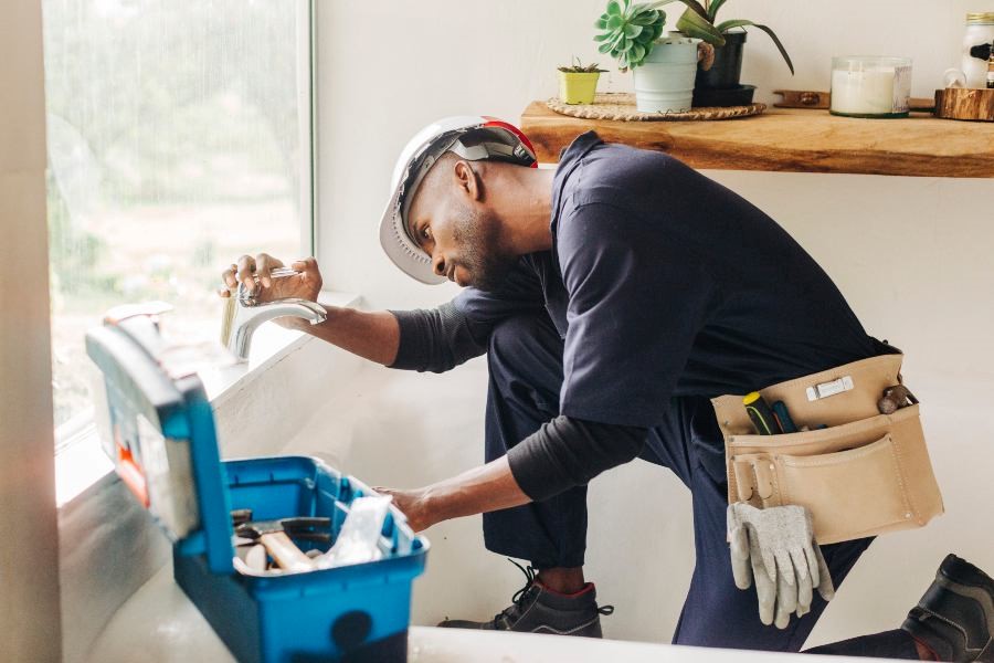 A man in a hat and gloves repairs a water heater in Atlanta, GA.