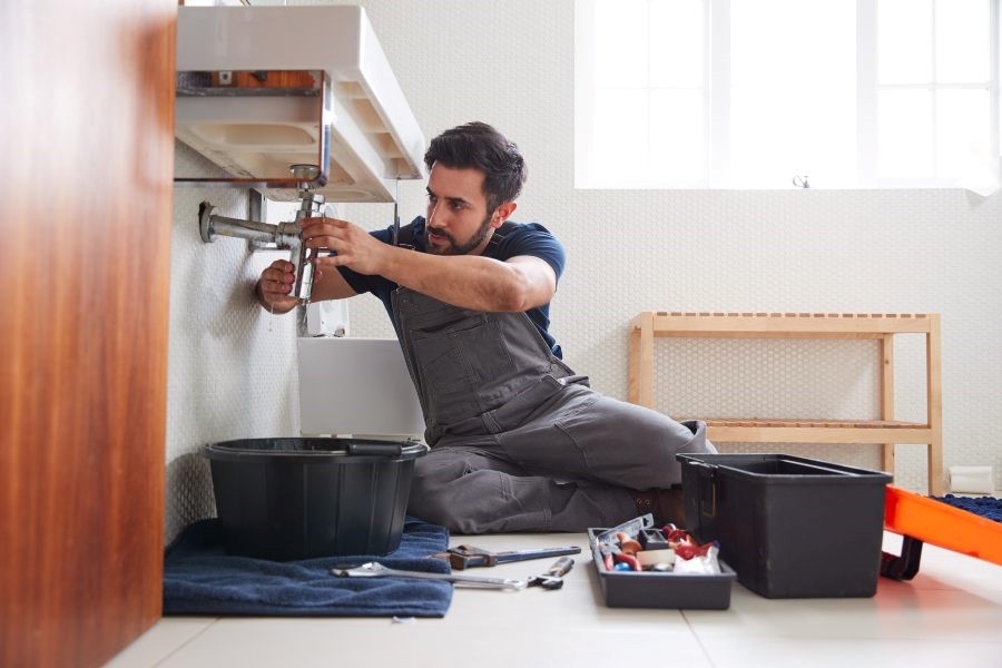 A man repairs a sink in Atlanta, GA, as water spills from the fixture.