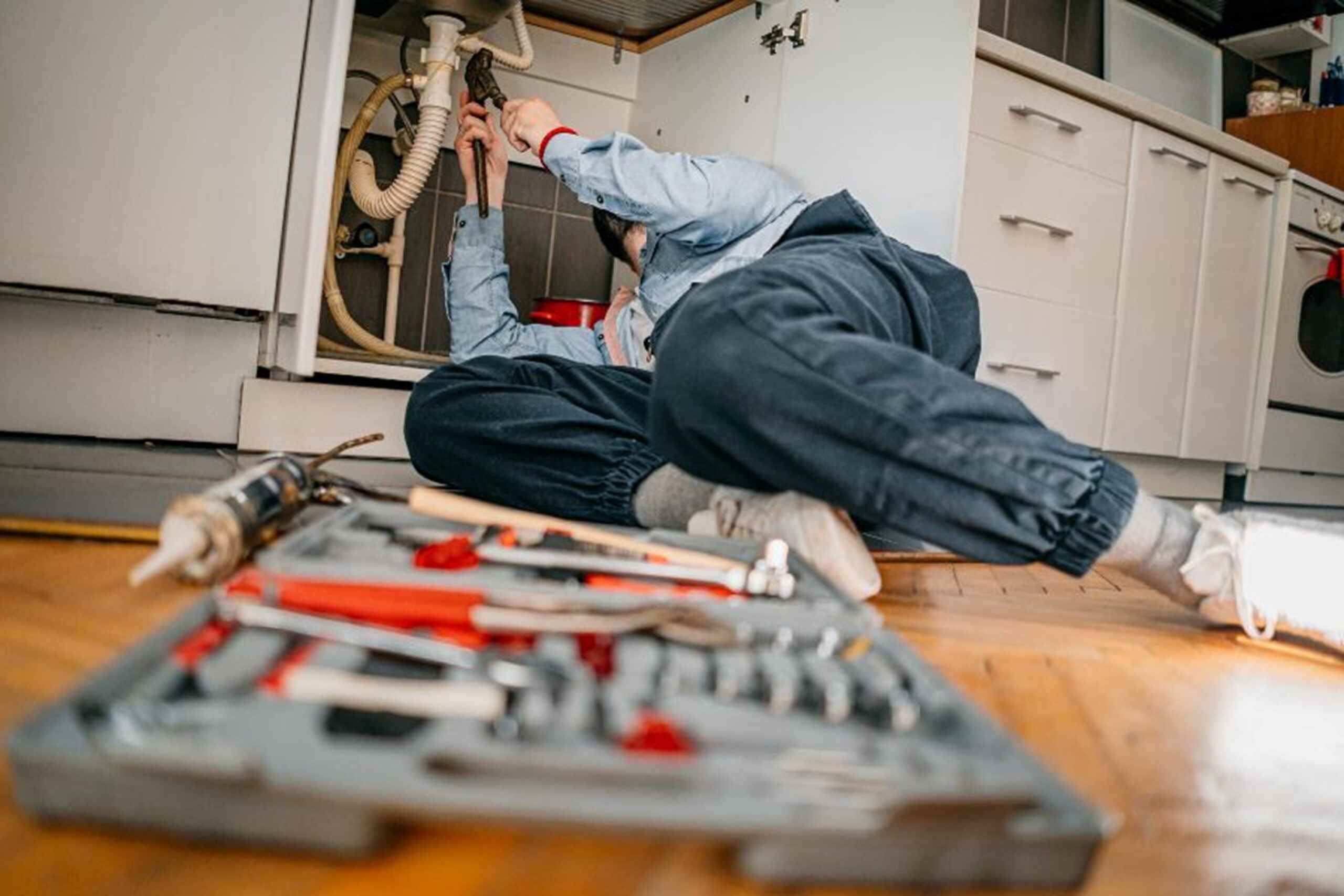A man is repairing a kitchen sink, providing emergency plumbing services in Hiram, GA.