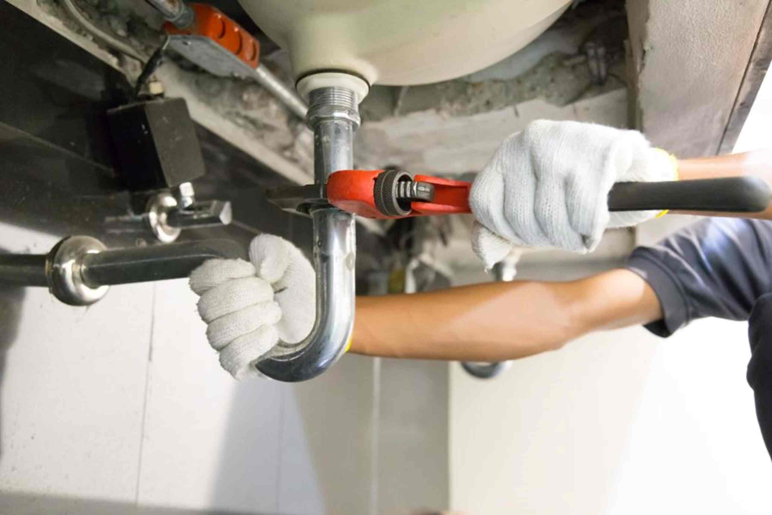 A man in white gloves repairs a pipe after detecting the leak in East Cobb, GA.