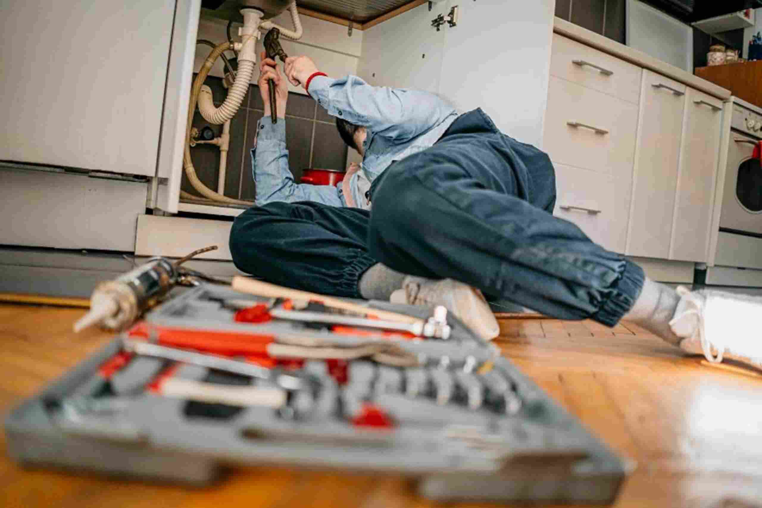 A man is repairing a kitchen sink, and providing emergency plumbing services in Hiram, GA.