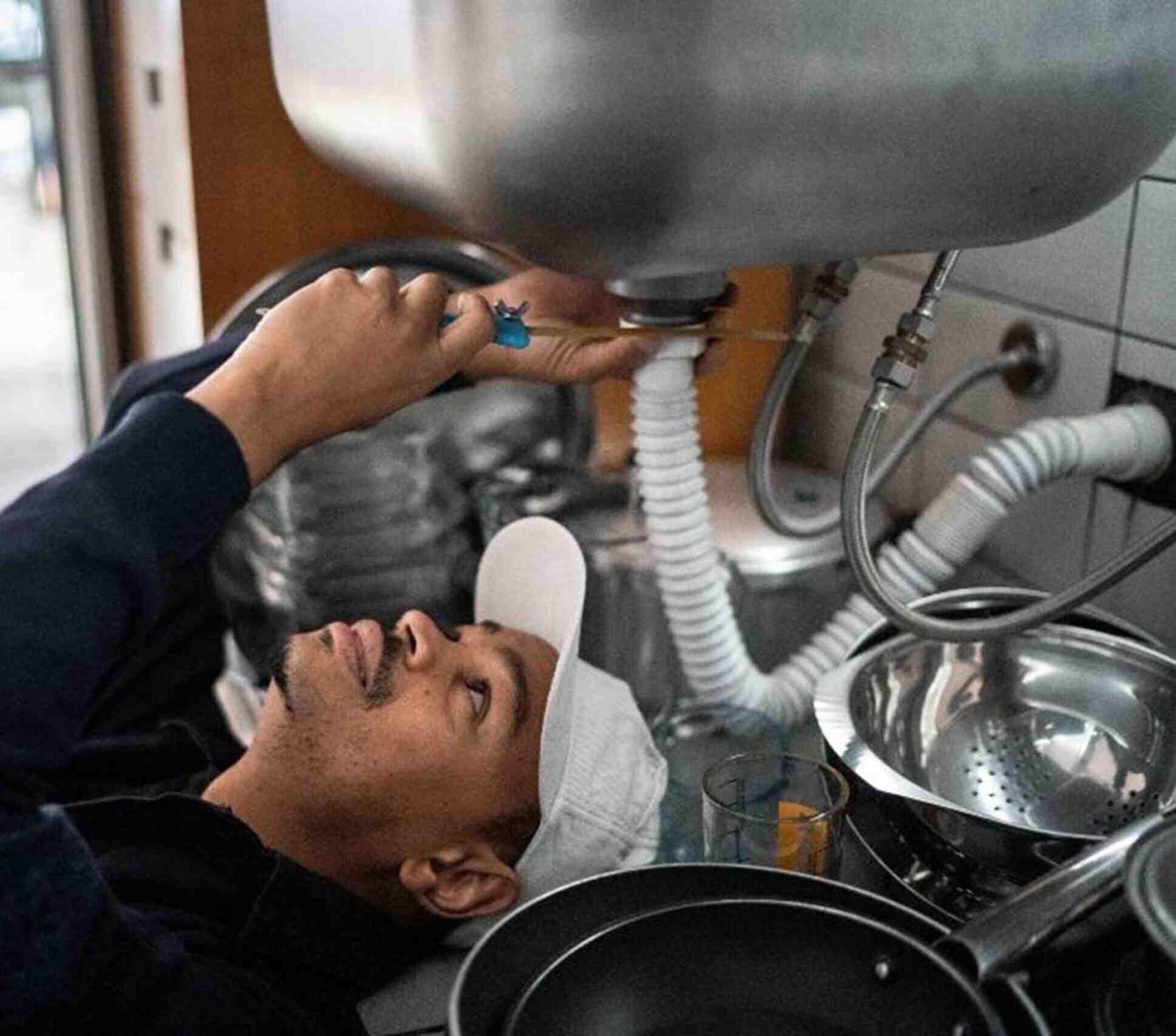 A man is repairing a kitchen sink, and providing emergency plumbing services in Powder Springs, GA.